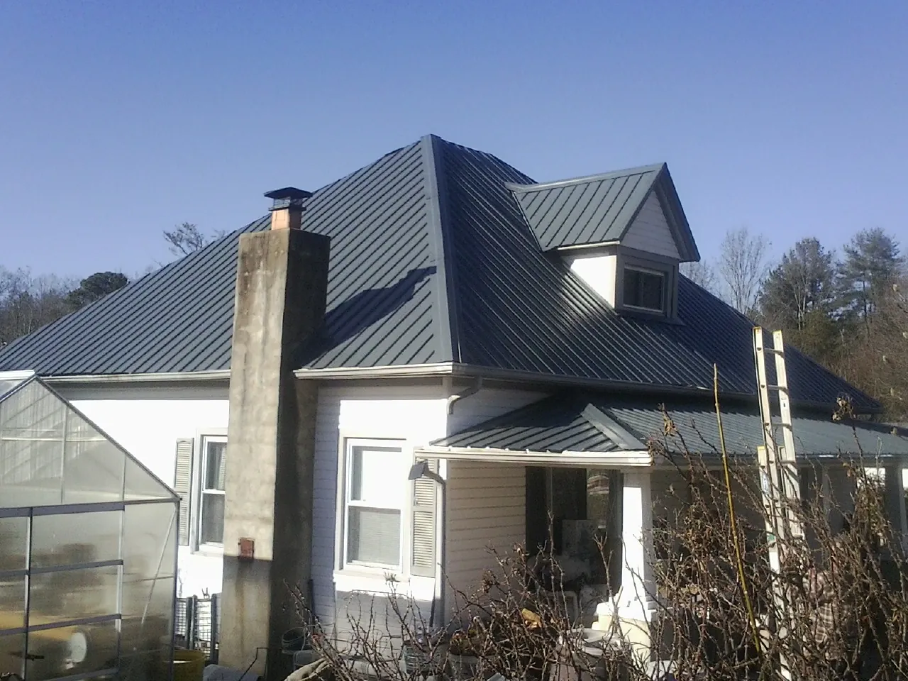 Dark blue standing seam metal roof on a white farmhouse with dormer — Slate & Tile Roof Repair by Roofing Brothers in Arendtsville