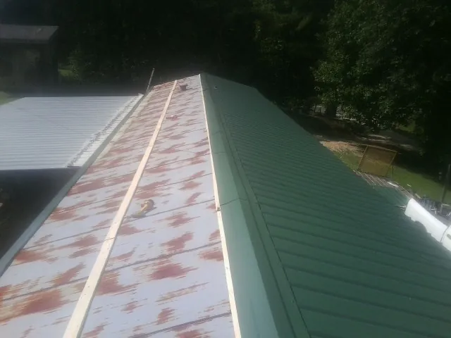 Old rusted panels beside newly installed green metal roofing — Wind Damage Roof Repair by Roofing Brothers in Arendtsville
