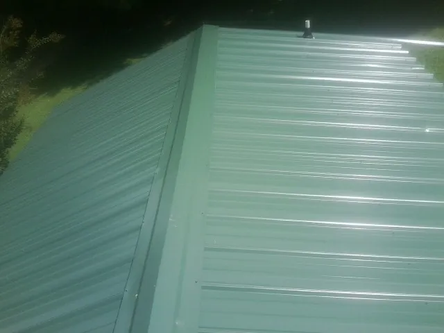 New green metal panels meeting at the ridge of a roof — Flat Roof Repair work by our crew in Arendtsville