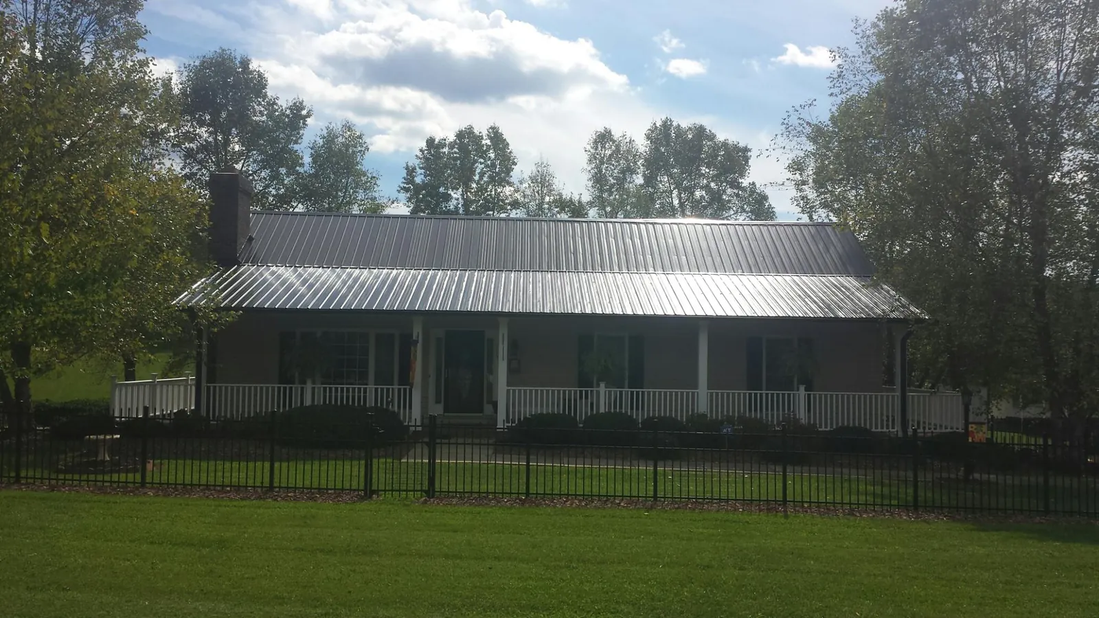 Gray metal roof on a brick ranch with a full width front porch — Gutter Guard Installation work by our crew in Arendtsville