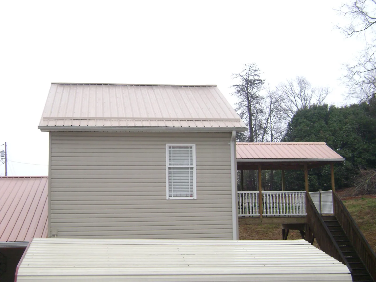 Tan metal roofs on a two story addition and attached porch, from a Roof Replacement job in Arendtsville