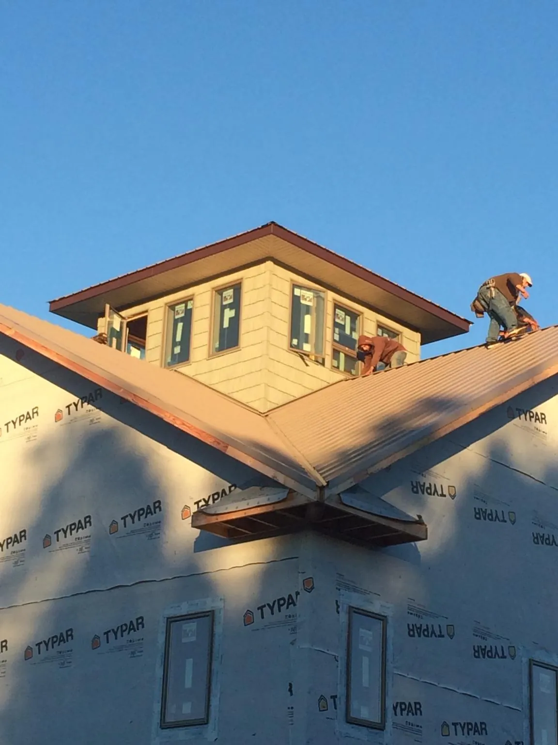 Roofers working around a rooftop cupola on a new metal roof at sunset — Roof Waterproofing in Arendtsville by Roofing Brothers
